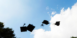 Doktorhüte Vier schwarze Doktorhüte fliegen in die Luft vor blauem Himmel mit weißen Wolken.